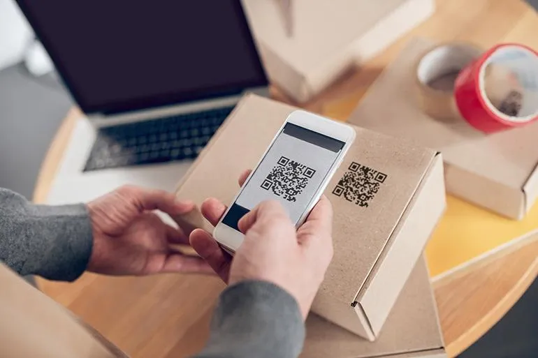 Een persoon die een QR-code scant op een doos met een telefoon