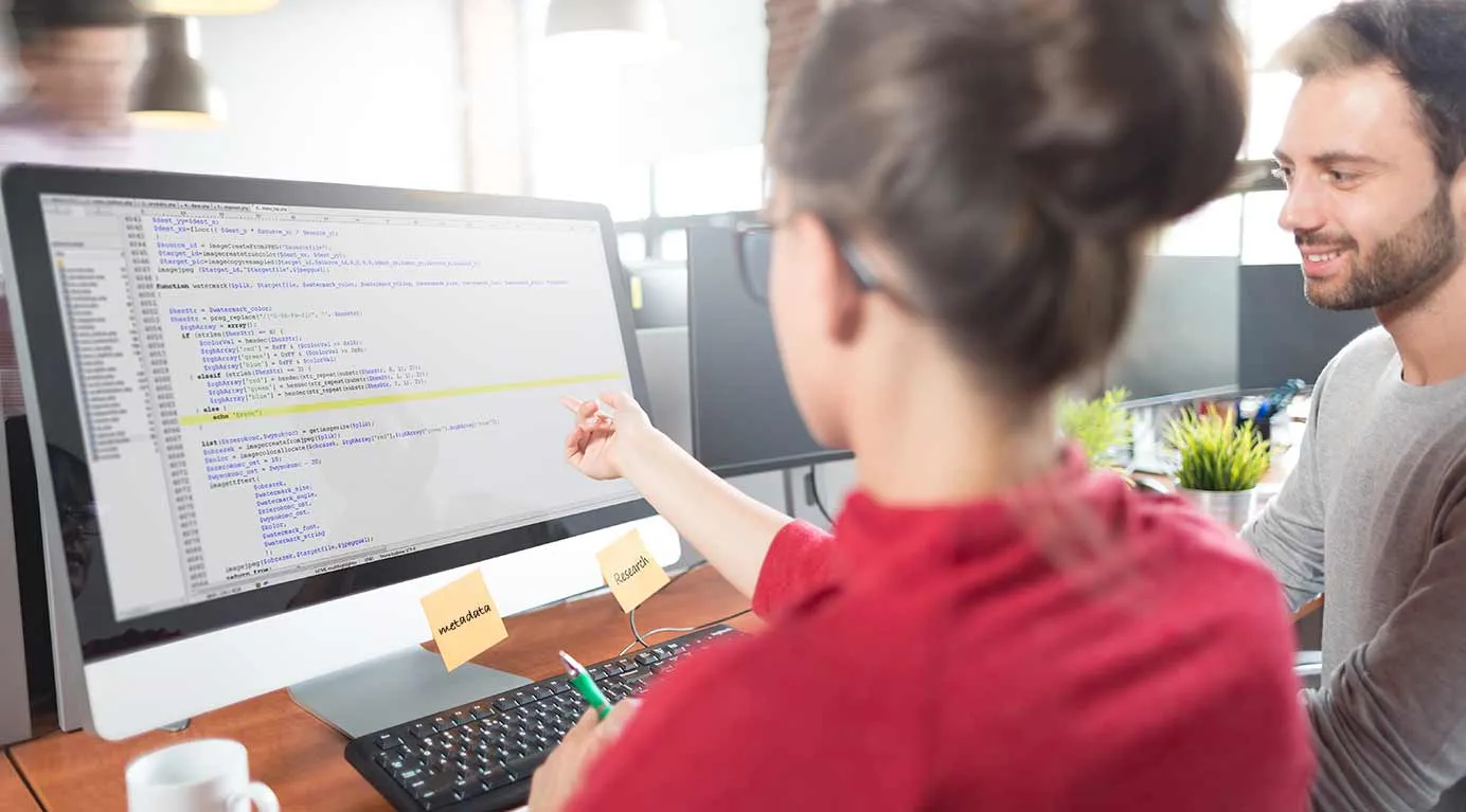 Een vrouw die wat uitlegt aan een man op een monitor